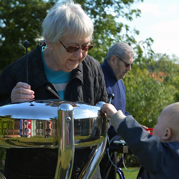 Older Lady and Small Child Playing Stainless Steel Tongue Drum Outdoors